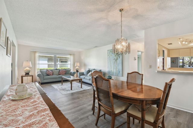 dining room with dark hardwood / wood-style floors, an inviting chandelier, and a textured ceiling