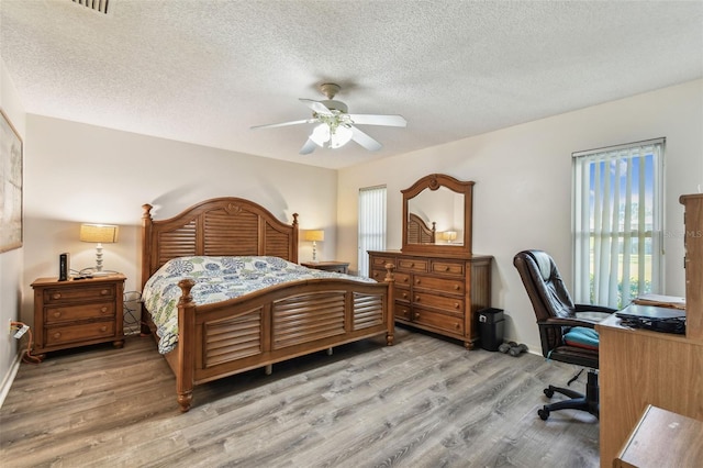 bedroom with ceiling fan, light hardwood / wood-style flooring, and a textured ceiling