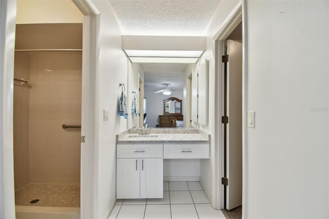 bathroom featuring vanity, tile patterned flooring, a textured ceiling, and a tile shower