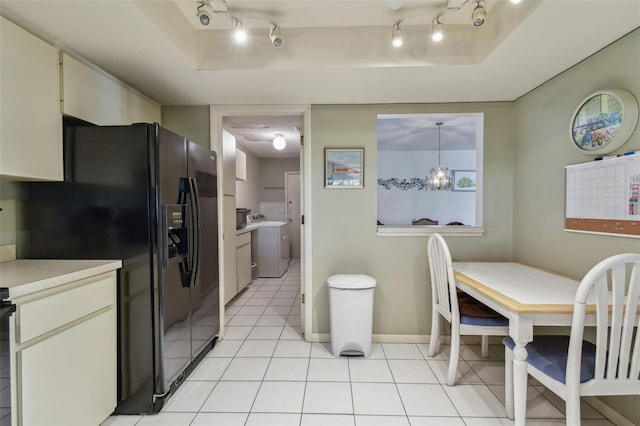 kitchen with pendant lighting, washer / clothes dryer, a raised ceiling, and black fridge