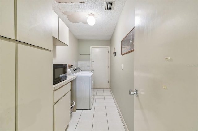 laundry area featuring light tile patterned flooring, a textured ceiling, and independent washer and dryer