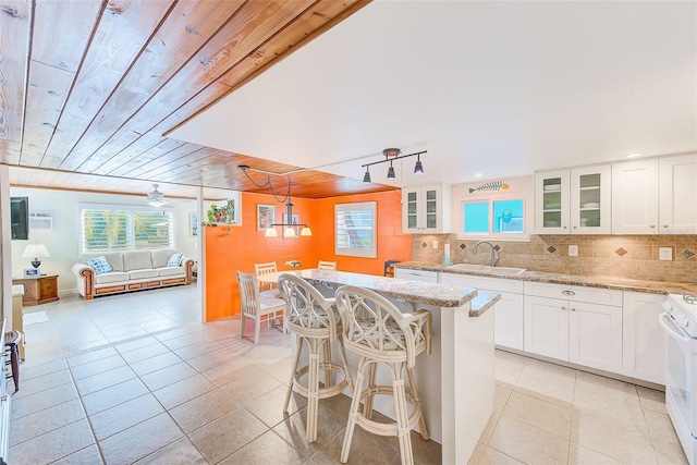 kitchen featuring pendant lighting, white cabinetry, sink, wood ceiling, and light stone counters