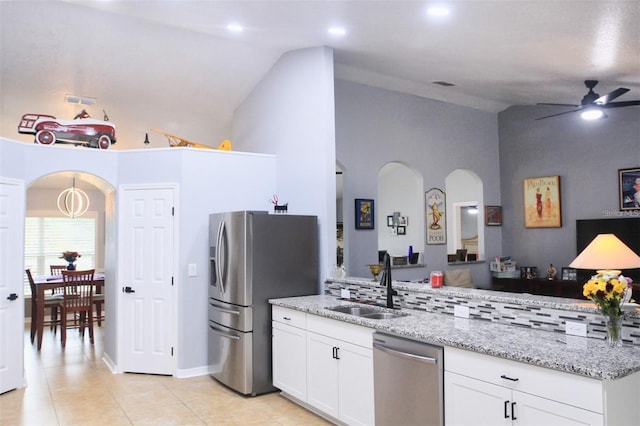 kitchen featuring vaulted ceiling, white cabinetry, sink, light stone counters, and stainless steel appliances