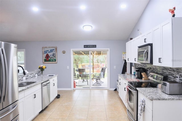 kitchen with sink, white cabinetry, appliances with stainless steel finishes, light stone countertops, and backsplash