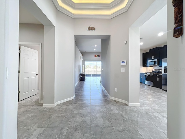 hallway featuring tile patterned flooring, ornamental molding, and a high ceiling