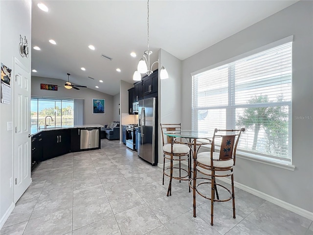 kitchen with light tile patterned flooring, a breakfast bar area, vaulted ceiling, appliances with stainless steel finishes, and ceiling fan