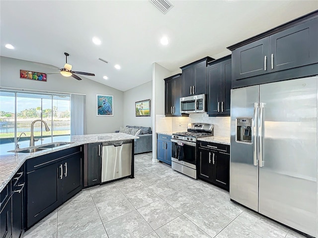 kitchen with vaulted ceiling, sink, decorative backsplash, stainless steel appliances, and light stone countertops