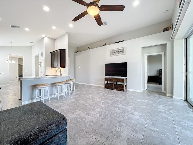 tiled living room with sink, ceiling fan with notable chandelier, and high vaulted ceiling