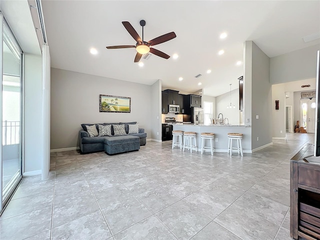 living room featuring ceiling fan, sink, and vaulted ceiling