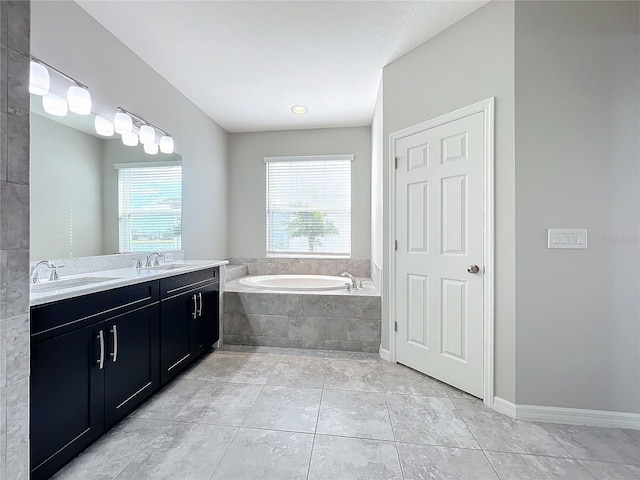 bathroom with a relaxing tiled tub, vanity, and tile patterned floors