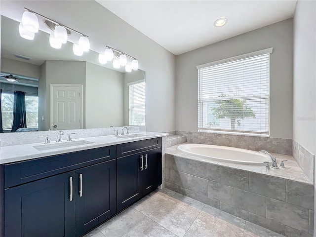 bathroom with a relaxing tiled tub, ceiling fan, vanity, and tile patterned flooring