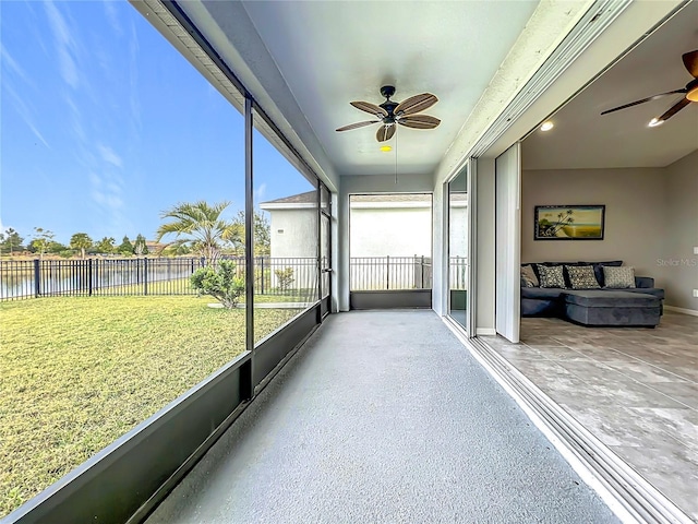 sunroom featuring ceiling fan and a water view