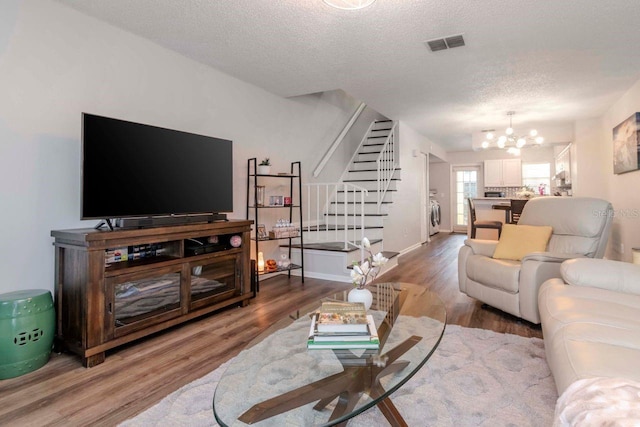 living room with a textured ceiling, wood-type flooring, washer / dryer, and a chandelier