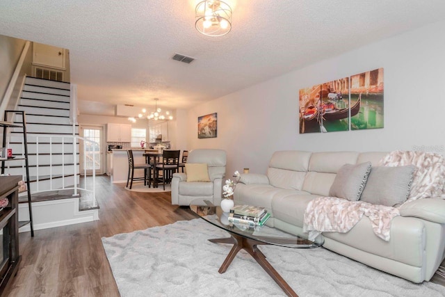 living room featuring a chandelier, hardwood / wood-style floors, and a textured ceiling