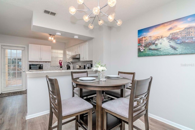 dining area with hardwood / wood-style floors, sink, and a chandelier