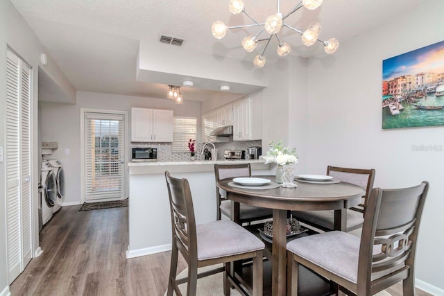 dining area with washing machine and clothes dryer, sink, a chandelier, and hardwood / wood-style floors