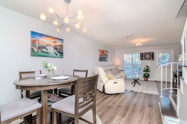 dining space featuring a chandelier, light hardwood / wood-style floors, and a textured ceiling