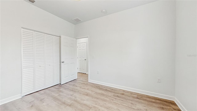 unfurnished bedroom with light wood-type flooring and a closet