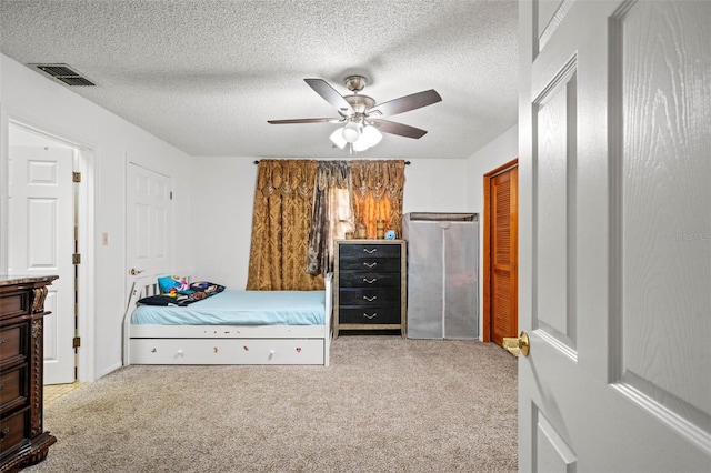 bedroom with ceiling fan, light carpet, and a textured ceiling