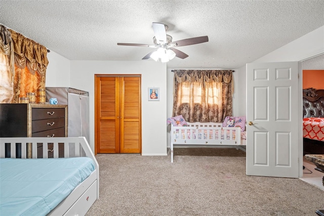 carpeted bedroom with ceiling fan, a textured ceiling, and a closet