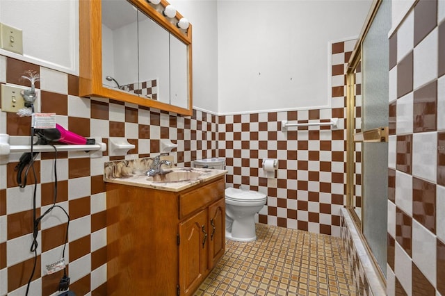 full bathroom featuring bath / shower combo with glass door, tile walls, tile patterned flooring, vanity, and toilet