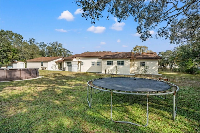 back of property featuring a trampoline and a yard