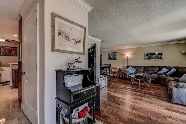 living room with hardwood / wood-style flooring, crown molding, and a textured ceiling