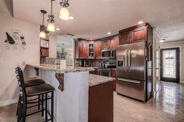 kitchen with a breakfast bar, hanging light fixtures, kitchen peninsula, stainless steel appliances, and light stone countertops