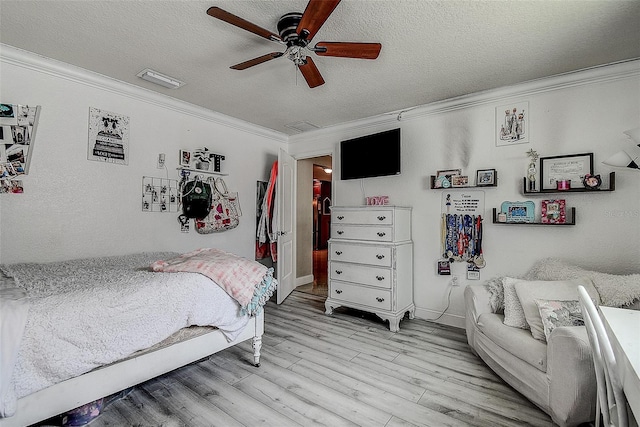 bedroom featuring ceiling fan, light hardwood / wood-style flooring, ornamental molding, and a textured ceiling