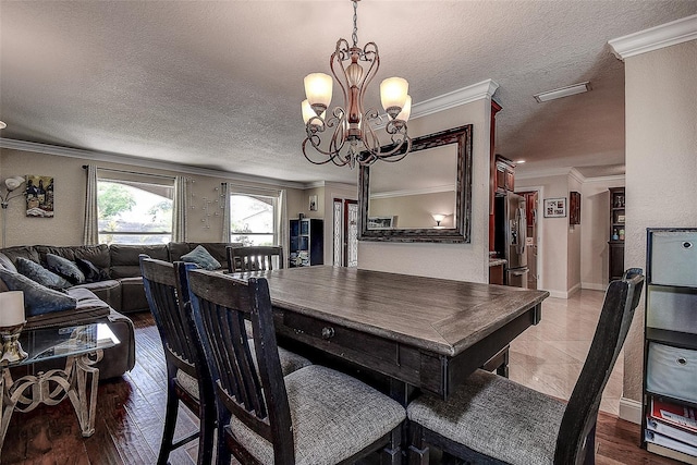 dining room featuring hardwood / wood-style flooring, ornamental molding, a textured ceiling, and an inviting chandelier