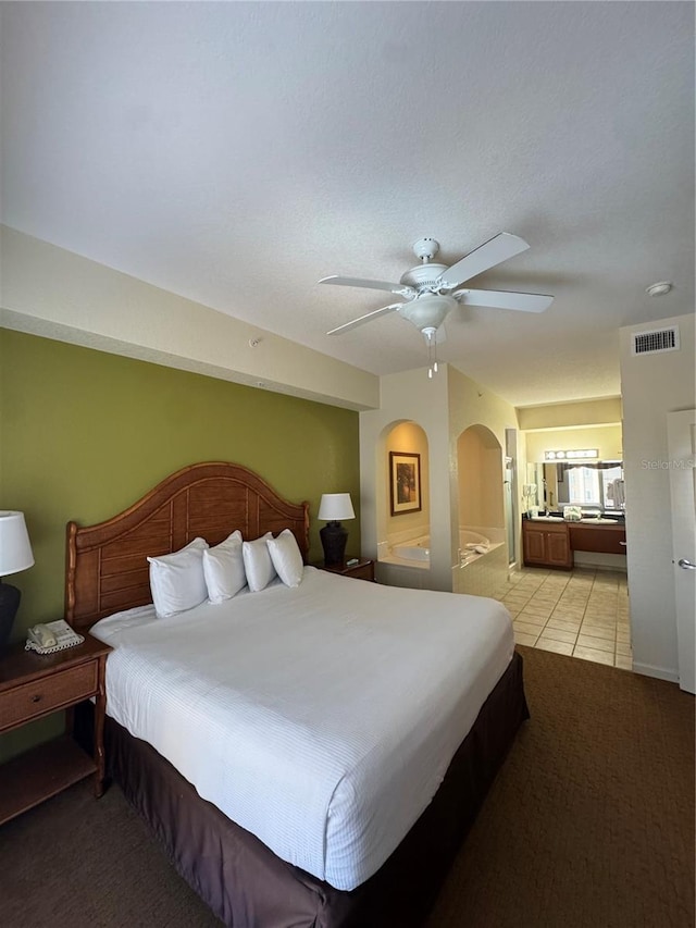 bedroom with light tile patterned floors, ceiling fan, and ensuite bathroom