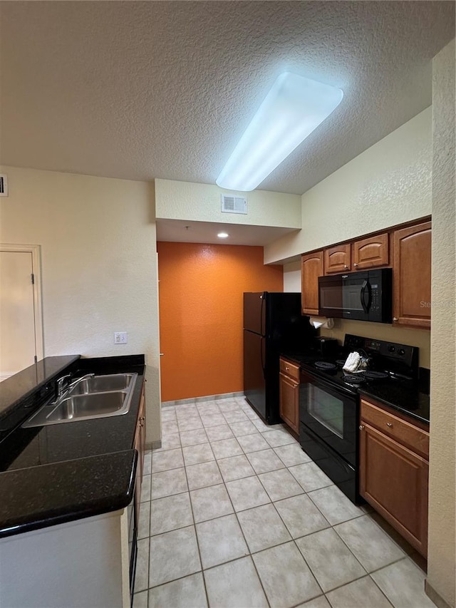 kitchen with light tile patterned floors, sink, a textured ceiling, and black appliances