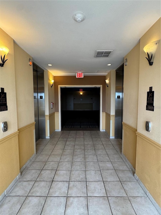 hallway featuring elevator and light tile patterned floors