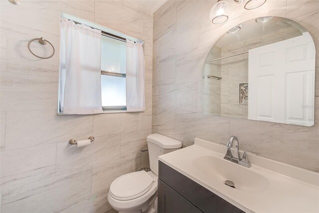 full bathroom with vanity, toilet, and tile walls
