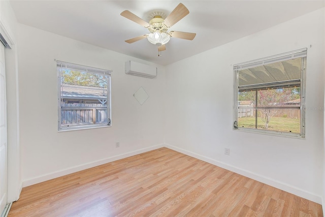 unfurnished room with light wood-type flooring, a wall mounted AC, baseboards, and a ceiling fan