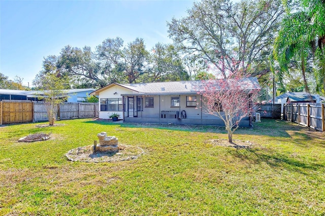 rear view of property featuring a lawn, a fenced backyard, and a sunroom