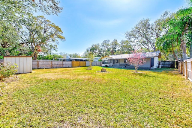 view of yard with an outdoor structure, a storage unit, and a fenced backyard