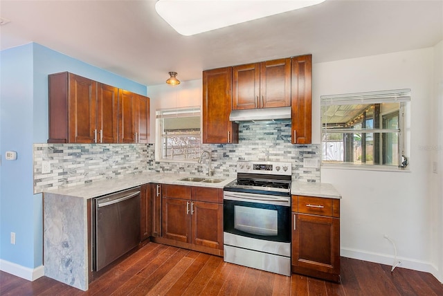 kitchen featuring dark wood finished floors, a sink, light countertops, under cabinet range hood, and appliances with stainless steel finishes