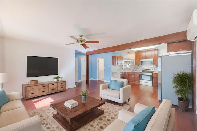 living room with baseboards, an AC wall unit, ceiling fan, and wood finished floors