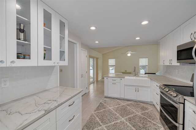 kitchen with white cabinetry, stainless steel appliances, light stone countertops, and sink