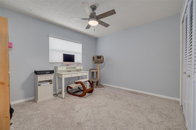 carpeted office space with ceiling fan and a textured ceiling