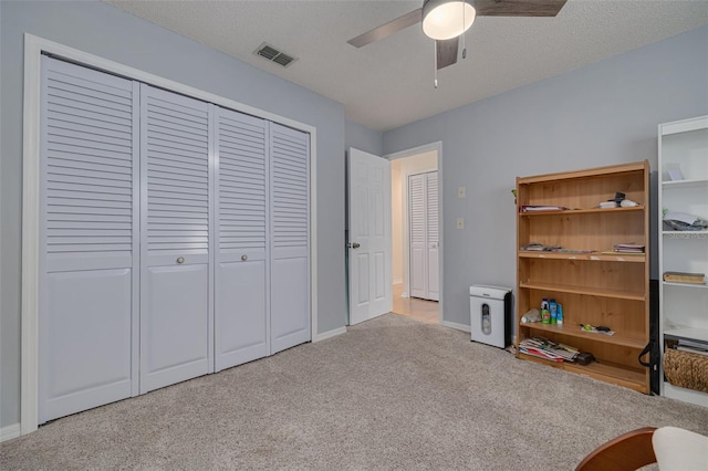 unfurnished bedroom with ceiling fan, a closet, light carpet, and a textured ceiling