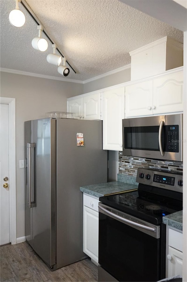 kitchen with white cabinetry, ornamental molding, appliances with stainless steel finishes, dark hardwood / wood-style flooring, and backsplash