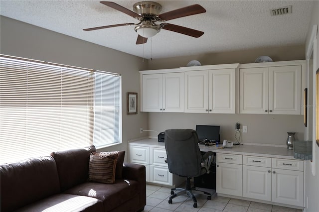 tiled office with ceiling fan, built in desk, and a textured ceiling