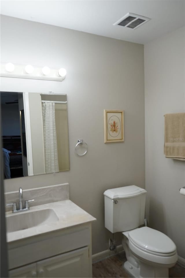 bathroom with hardwood / wood-style flooring, vanity, and toilet