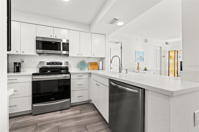 kitchen with white cabinetry, sink, kitchen peninsula, and appliances with stainless steel finishes