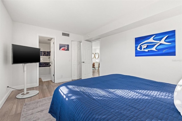 bedroom with ensuite bathroom and hardwood / wood-style floors