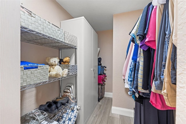 walk in closet with light hardwood / wood-style floors