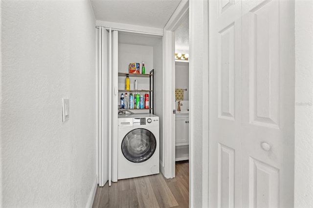 washroom featuring washer / clothes dryer, light hardwood / wood-style flooring, and a textured ceiling