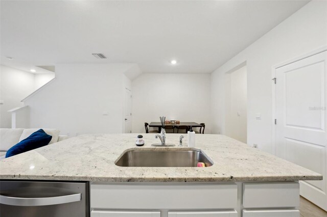 kitchen with white cabinetry, sink, and a kitchen island with sink